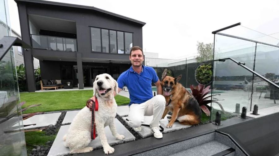 Rick Williams and his two dogs, Oscar and Louis, at the waterfront home he has listed in Newport, Brisbane. 